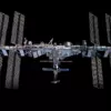 Международная космическая станция на фоне чёрного космоса: длинная ферма с четырьмя парами солнечных батарей и модули в центре, снимок с корабля Crew Dragon в 2021 году