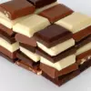 Сложенные стопкой дольки тёмного, молочного и белого шоколада