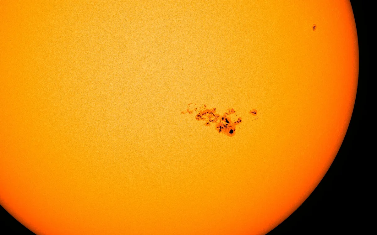 Крупная группа солнечных пятен на оранжевом диске Солнца, снимок SDO 9 мая 2024 года